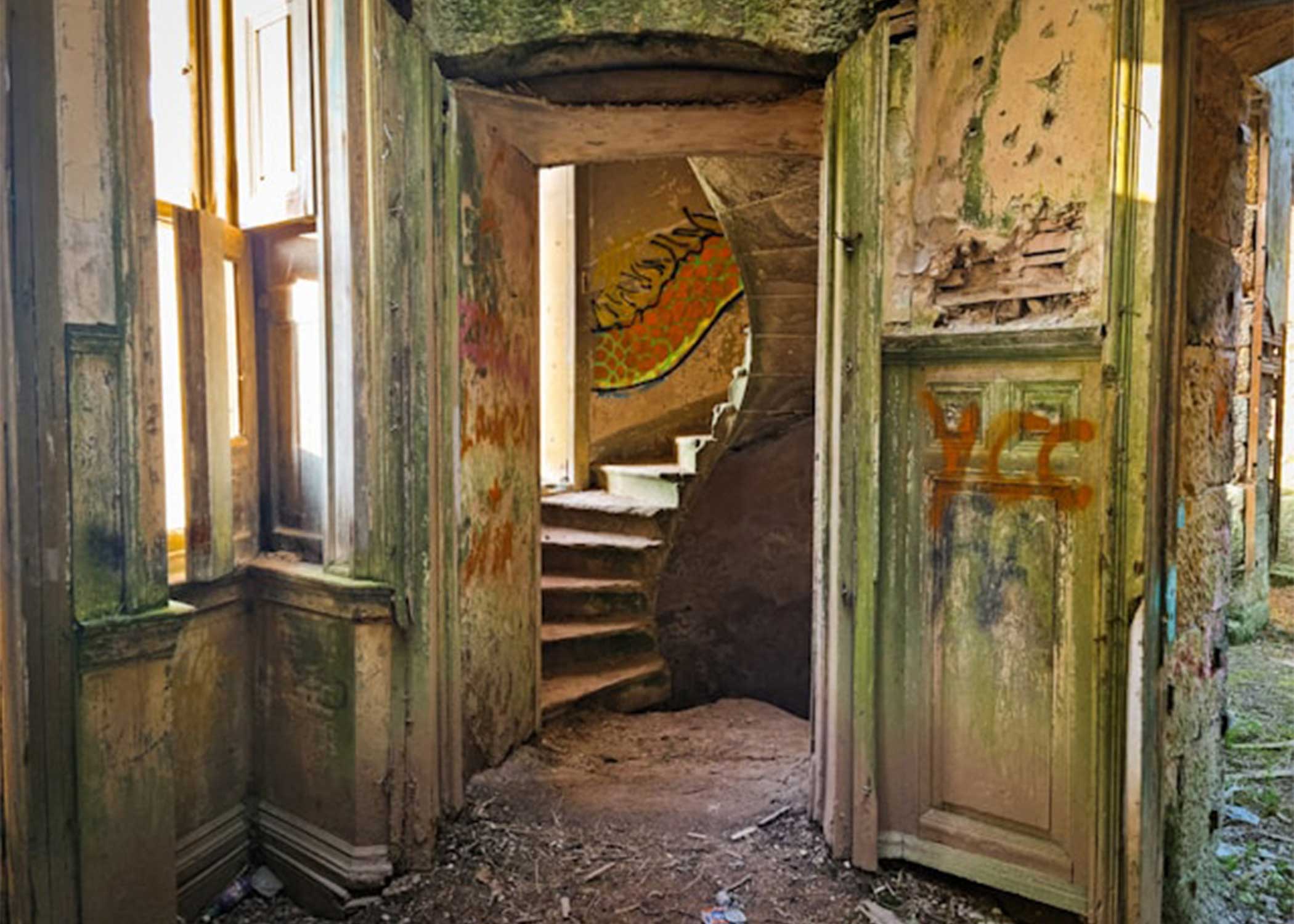Abandoned stairwell with peeling paint and sunlight through doorway